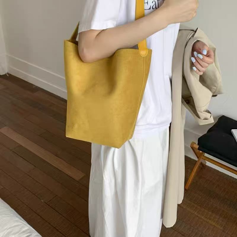 Amoirelle Saffron mustard yellow bucket tote worn on the shoulder