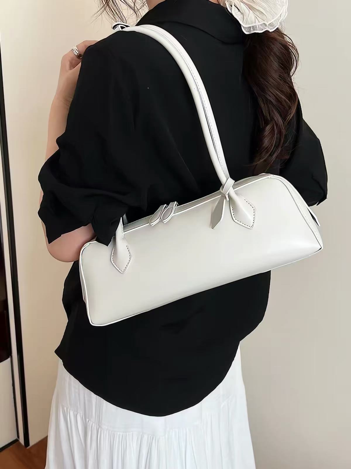 Solenne ivory elongated shoulder bag worn on the shoulder, rear three-quarter view