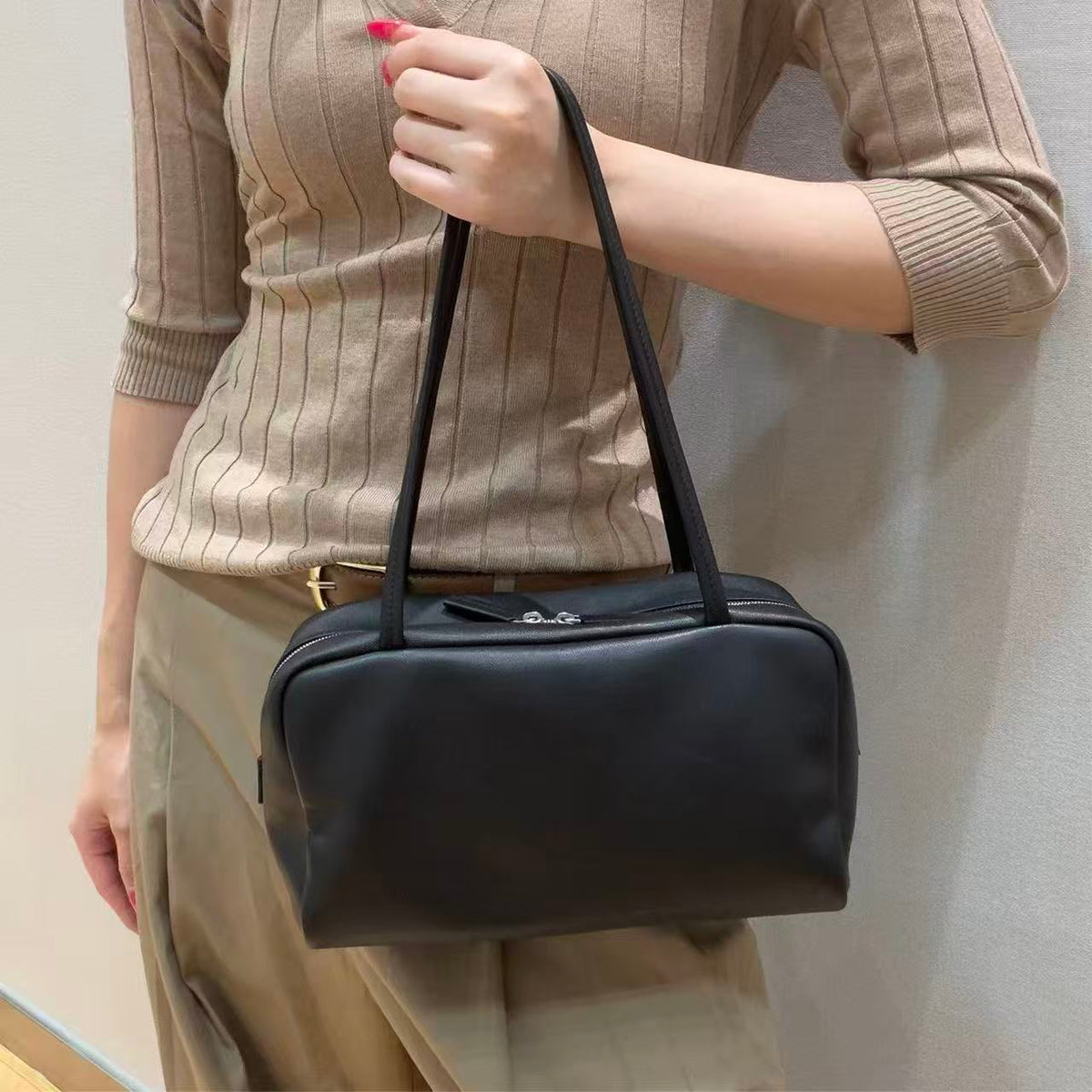 Vesper black rectangular shoulder bag carried by hand, showing twin long straps